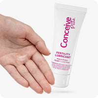 Conceive Plus Fertility Lubricant Combo Saver (IT) featuring a hand holding a clear drop of fertility lubricant next to a 75ml tube, emphasizing texture and consistency for conception use.