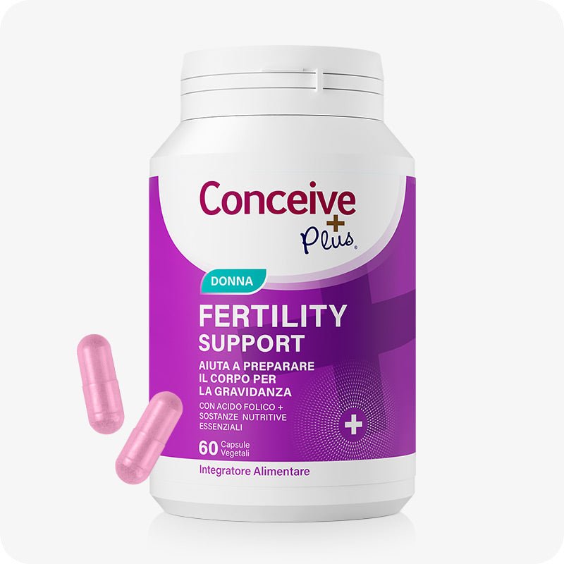 Conceive Plus Women's Fertility Support (IT) bottle with purple and white label showing 60 vegetarian capsules, placed upright with two pink capsules beside it, designed to support female fertility and reproductive health in Italian market.